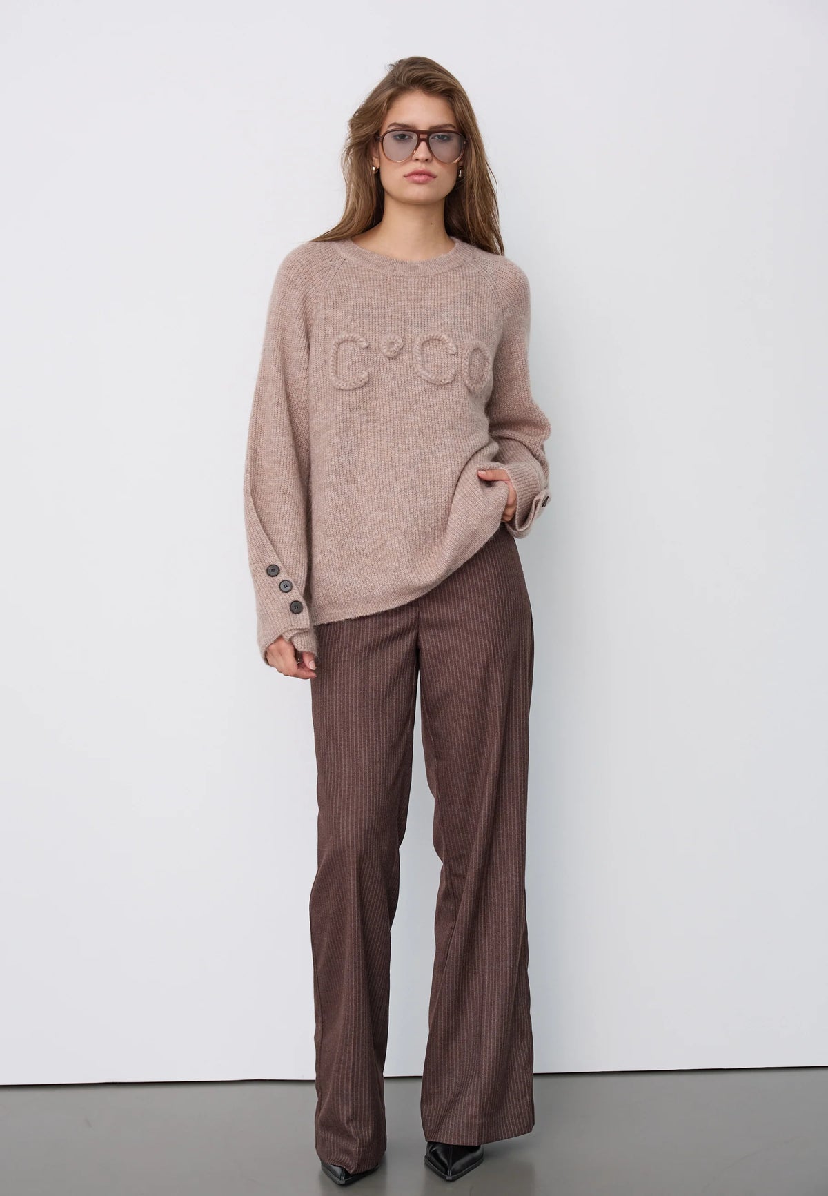 Co’Couture AelleCC Knit -neulepusero ruskeassa Walnut-sävyssä. Väljä istuvuus, kirjailtu teksti rinnassa ja koristenapit hihansuissa.