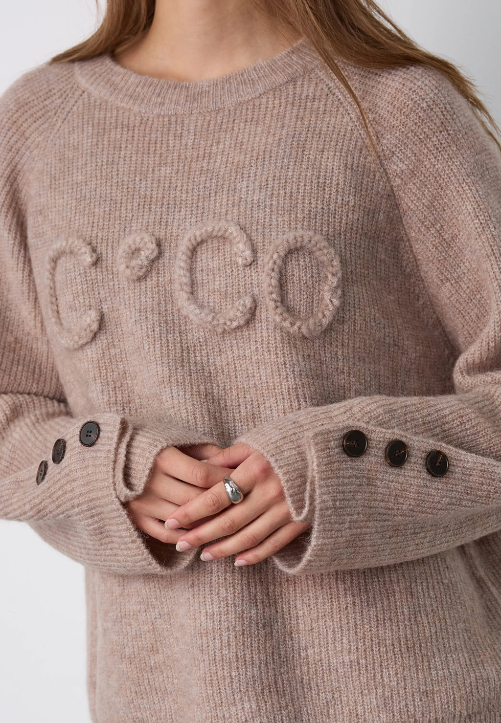 Co’Couture AelleCC Knit -neulepusero ruskeassa Walnut-sävyssä. Väljä istuvuus, kirjailtu teksti rinnassa ja koristenapit hihansuissa.