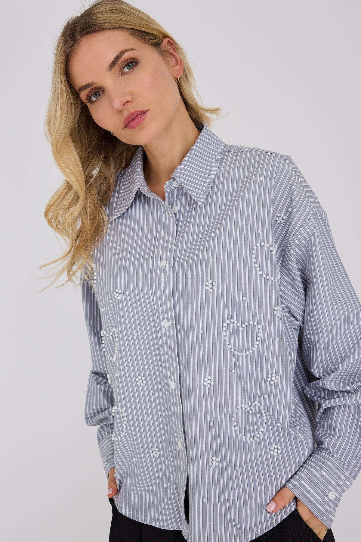 Lucie Shirt on rento raidallinen pusero, jossa kauniit kukkamaiset helmiäiskirjailut tuovat naisellisen ja hieman ylellisen yksityiskohdan.