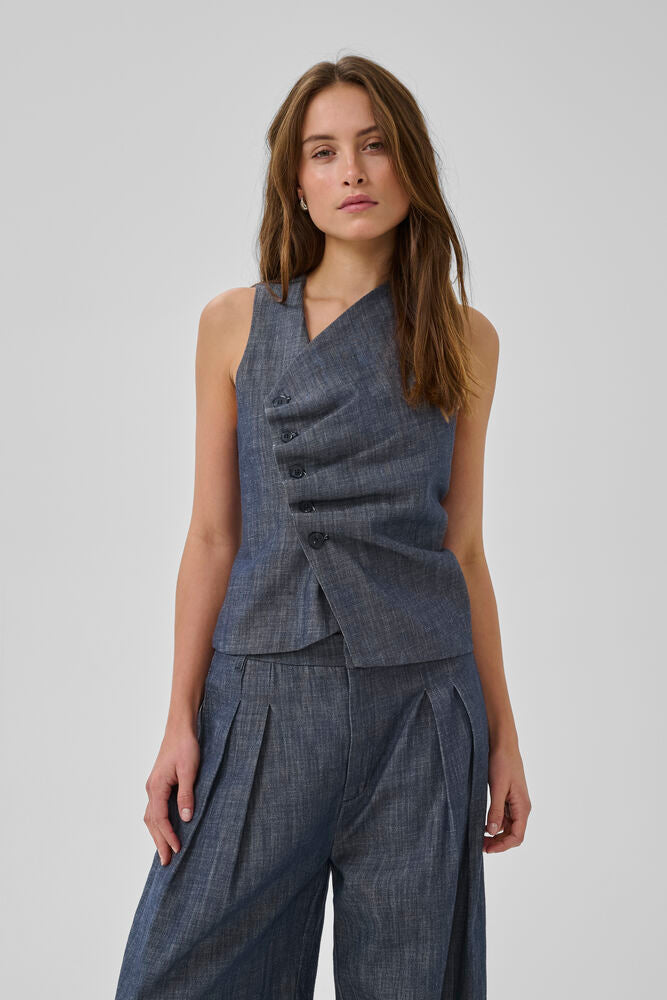 Tummansininen farkkuliivi, epäsymmetrisellä nappikiinnityksellä. Kaunis ja naisellinen istuva malli.