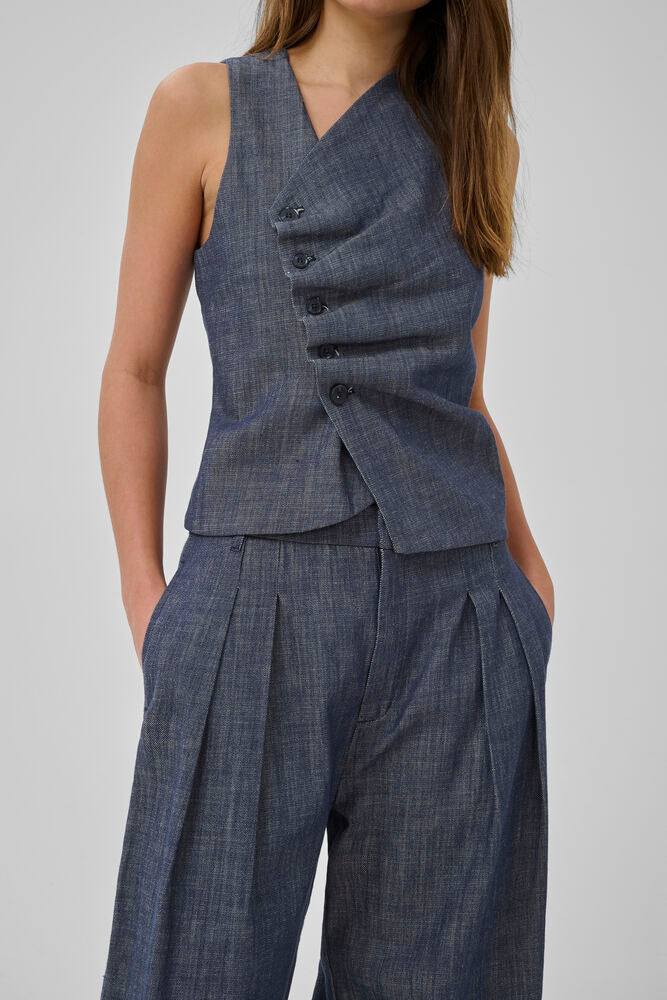 Tummansininen farkkuliivi, epäsymmetrisellä nappikiinnityksellä. Kaunis ja naisellinen istuva malli.