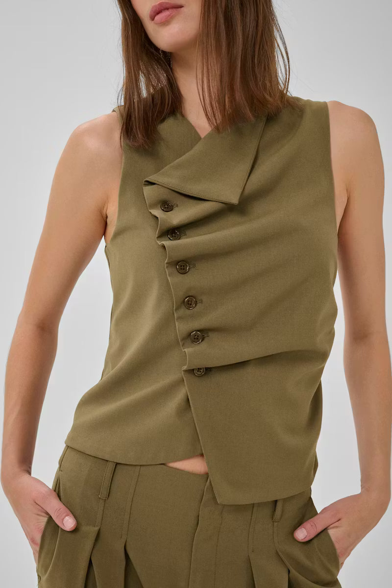 Tämä naisellinen hihaton toppi yhdistää modernin ilmeen ja arjen käyttömukavuuden. Epäsymmetrinen nappikiinnitys ja kauniisti istuva rypytetty etuosa tuovat paidalle hauskaa ilmettä.