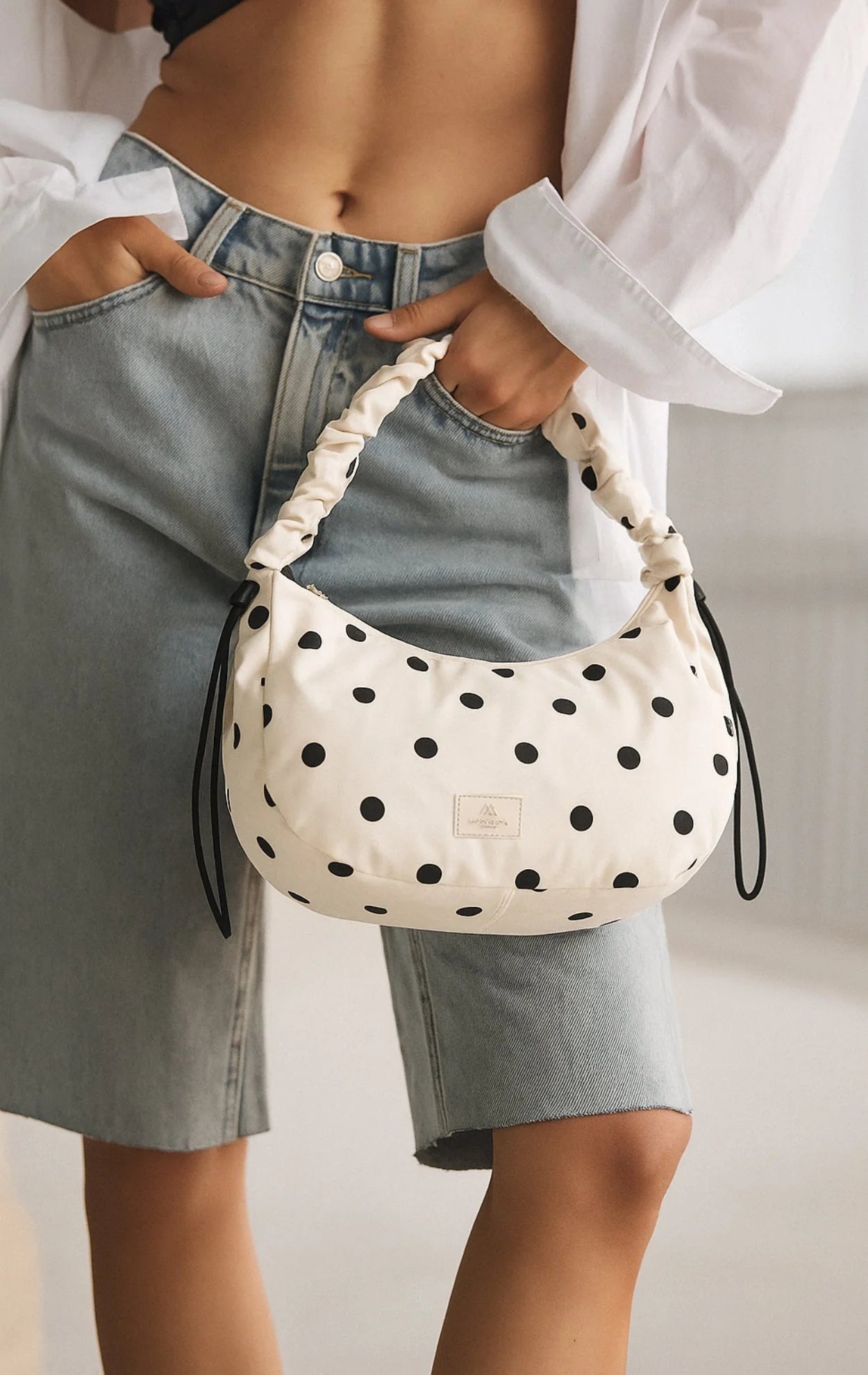 Tämä käytännöllinen mutta leikkisä laukku yhdistää sporttisen ilmeen ja huolitellun tyylin. Pilkullinen kuosi tuo asuun raikkautta, ja rypytetty, pehmeästi topattu hihna viimeistelee modernin kokonaisuuden.