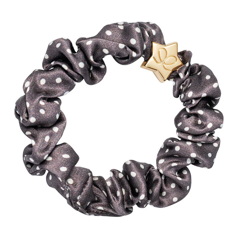 byEloise Silk Scrunchie on kaunis hiusasuste, jossa yhdistyvät ylellinen silkkimäinen materiaali ja kullanvärinen koriste. Pehmeä pompula on hellävarainen hiuksille ja viimeistelee kampauksen tyylikkäällä tavalla.