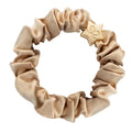 byEloise Silk Scrunchie on kaunis hiusasuste, jossa yhdistyvät ylellinen silkkimäinen materiaali ja kullanvärinen koriste. Pehmeä pompula on hellävarainen hiuksille ja viimeistelee kampauksen tyylikkäällä tavalla.