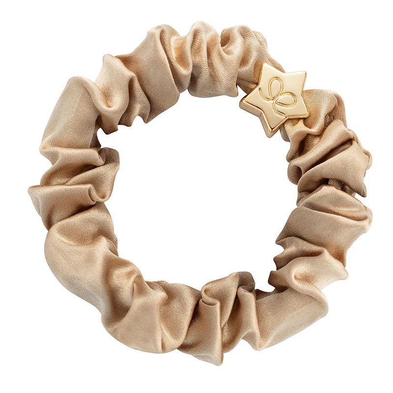 byEloise Silk Scrunchie on kaunis hiusasuste, jossa yhdistyvät ylellinen silkkimäinen materiaali ja kullanvärinen koriste. Pehmeä pompula on hellävarainen hiuksille ja viimeistelee kampauksen tyylikkäällä tavalla.