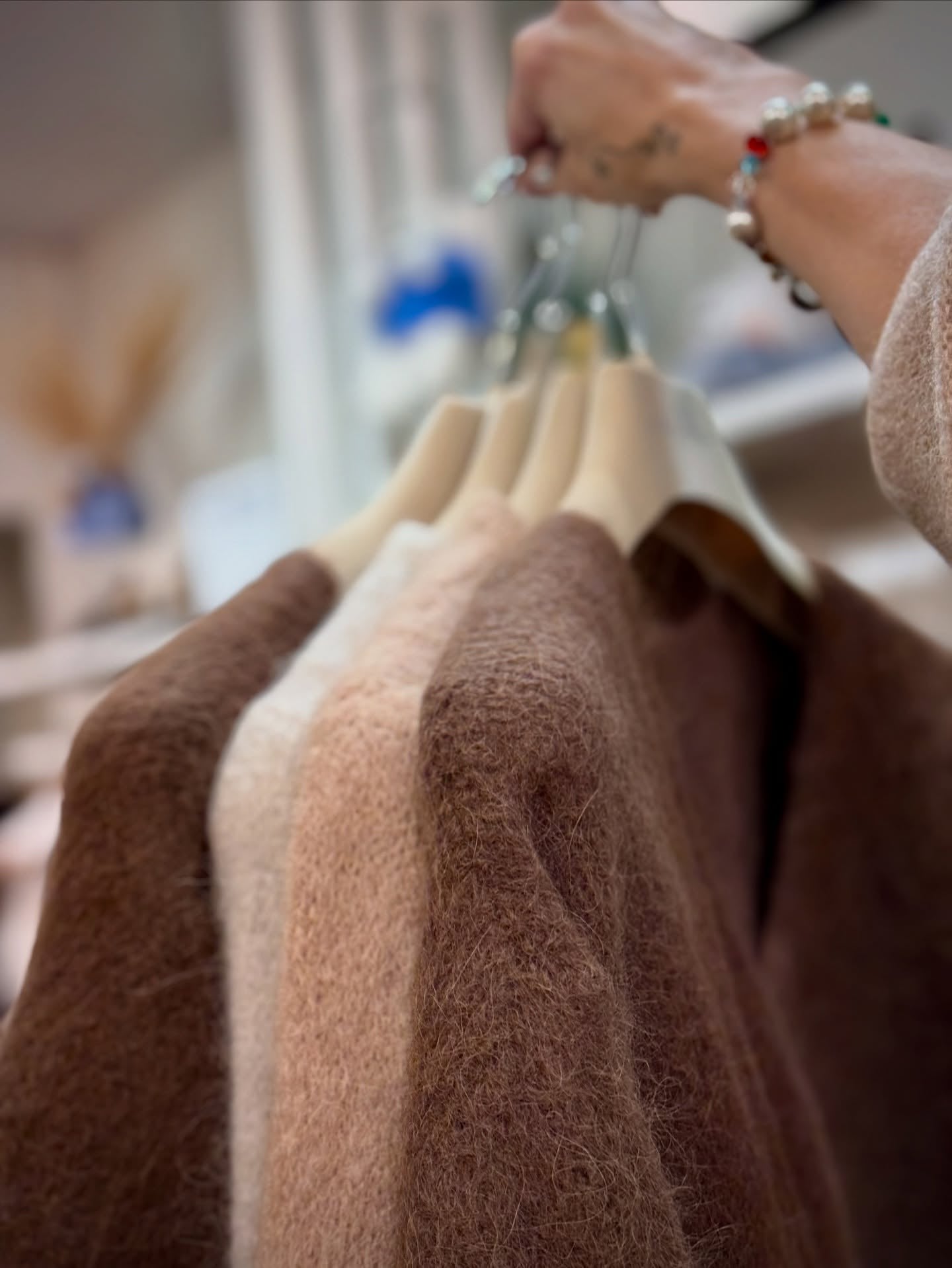 Ruskeita pörröisiä neulepaitoja henkarissa.