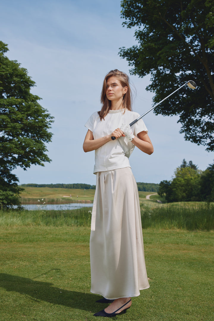 Tämä kaunis WeckiaBBSurina-hame hurmaa laskeutuvuudellaan ja elegantilla, ajattomalla ilmeellään. Kevyesti hohtava kangas antaa hameelle ryhtiä, mutta säilyttää samalla pehmeän ja naisellisen liikkeen. Hame, joka toimii monessa tilanteessa.