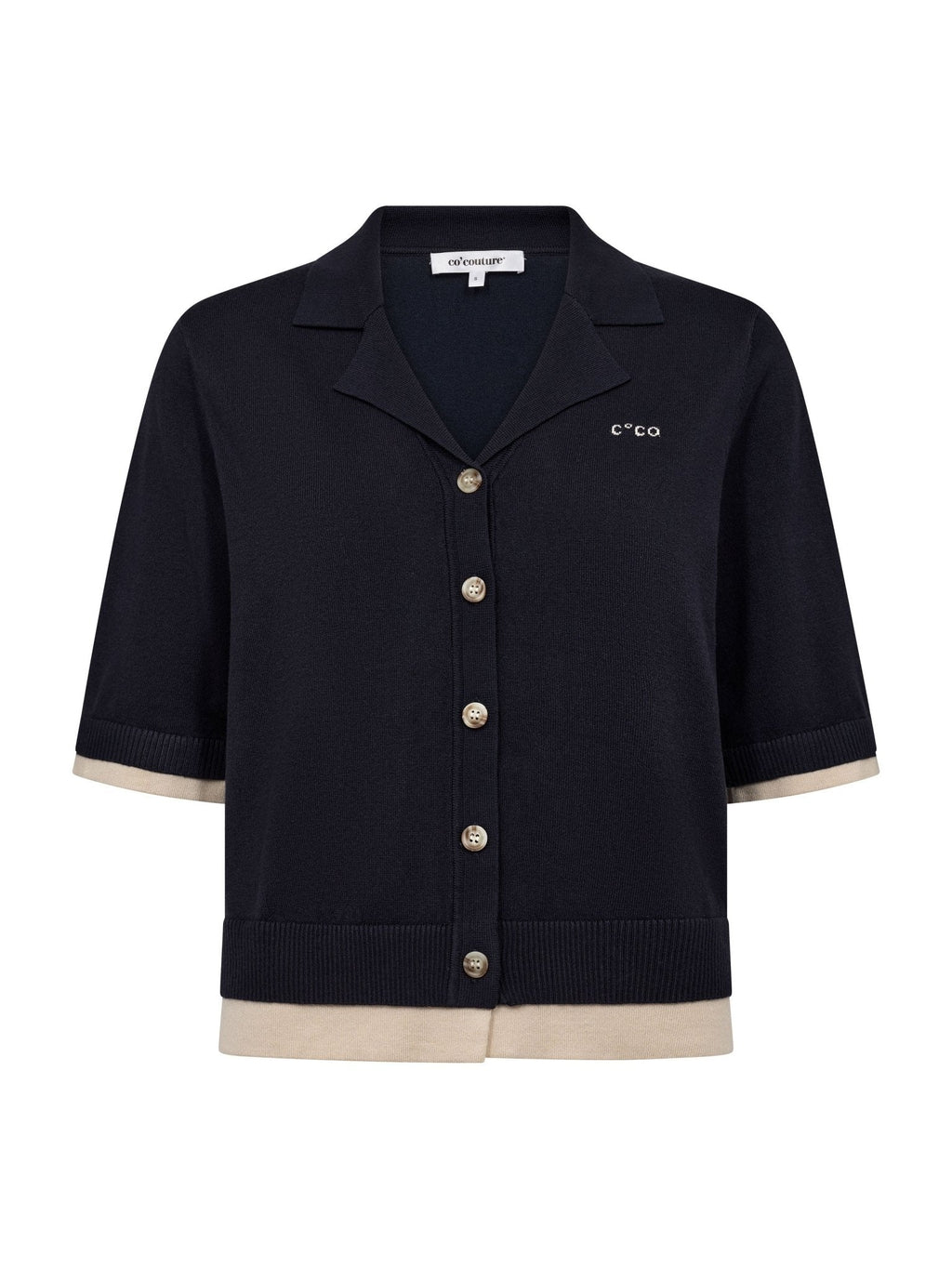 Co’Couture LueCC Crop Cardigan on lyhyt tummansininen neuletakki, jossa on kaulus, lyhyet hihat ja nappikiinnitys. Väljä malli sopii helposti kerrostamiseen.